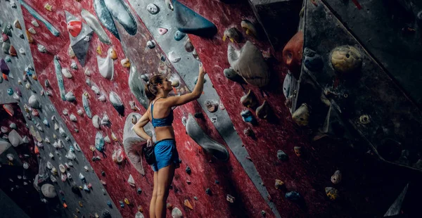 Wspinacz kobiece bouldering w pomieszczeniu. — Zdjęcie stockowe