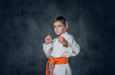Beyaz karate kimonosu giymiş bir çocuk.