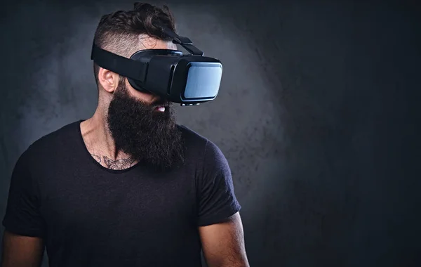 Um homem com tatuagens nos braços usando óculos VR . — Fotografia de Stock