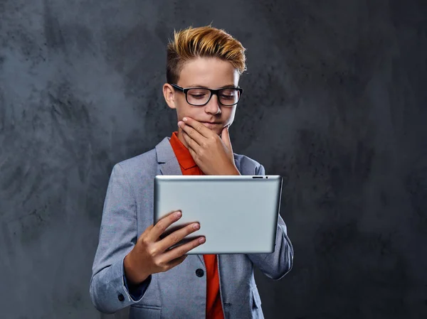 Um menino em óculos segura tablet PC . — Fotografia de Stock