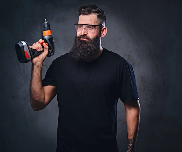 Bearded male holds a drill — Stock Photo, Image