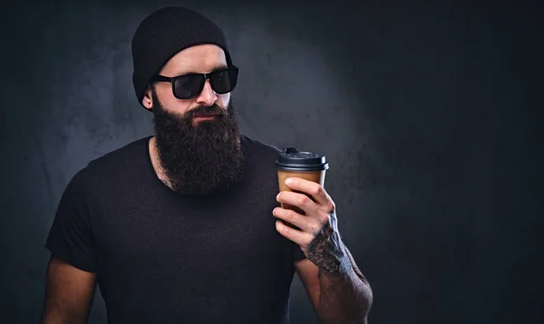 Bärtiger tätowierter Mann hält Kaffeetasse in der Hand. — Stockfoto