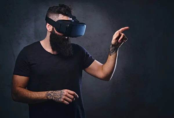 Um homem com tatuagens nos braços usando óculos VR . — Fotografia de Stock