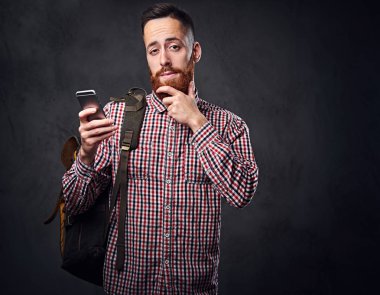 Kırmızı yün gömlekli bir adam akıllı telefon tutar.