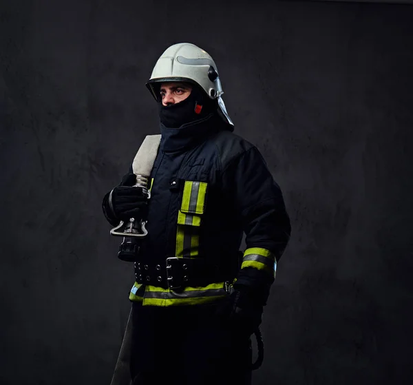 Bombero en uniforme sostiene manguera de fuego . — Foto de Stock