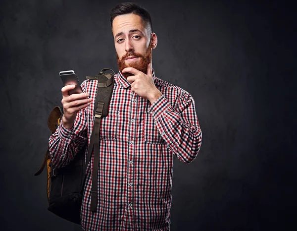 Kırmızı yün gömlekli bir adam akıllı telefon tutar.