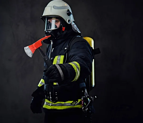 Bombeiro de uniforme segura um machado vermelho . — Fotografia de Stock