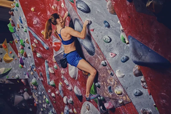 Professionele vrouwelijke klimmer op een muur boulderen. — Stockfoto