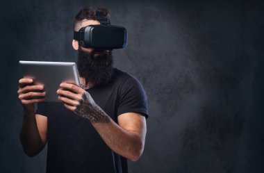 VR giyen bir adam gözlük ve tablet Pc tutar.