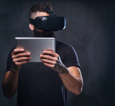 VR giyen bir adam gözlük ve tablet Pc tutar.