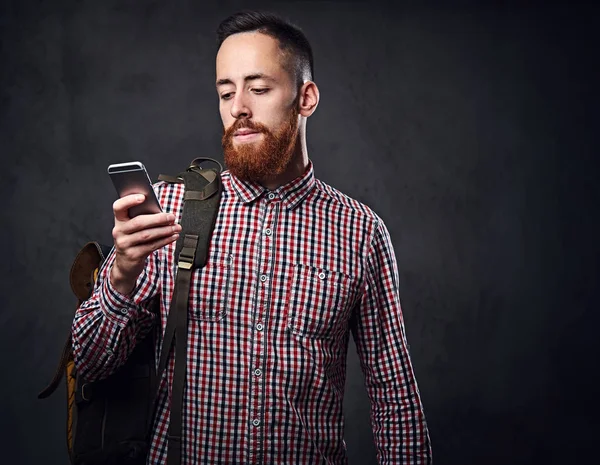 Un hombre con una camisa de lana roja sostiene el teléfono inteligente . —  Fotos de Stock