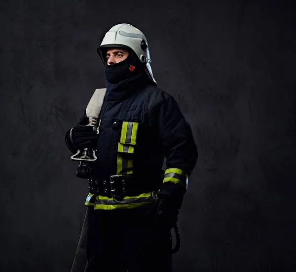 Hasič v jednotné drží požární hadice. — Stock fotografie