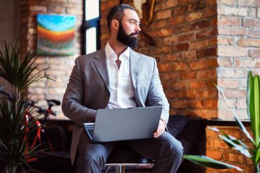 Şık sakallı erkek ile bir dizüstü bilgisayar çalışır