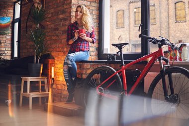 Sarışın kadın pencerenin sıcak kahve içer.