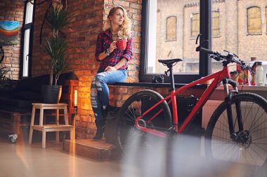 Sarışın kadın pencerenin sıcak kahve içer.