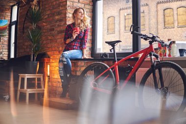 Sarışın kadın pencerenin sıcak kahve içer.