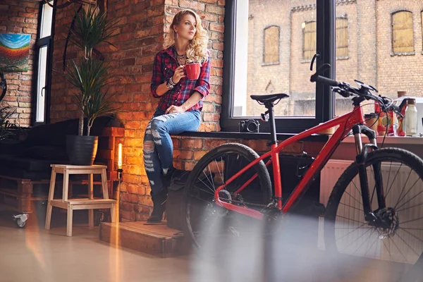 Sarışın kadın pencerenin sıcak kahve içer.