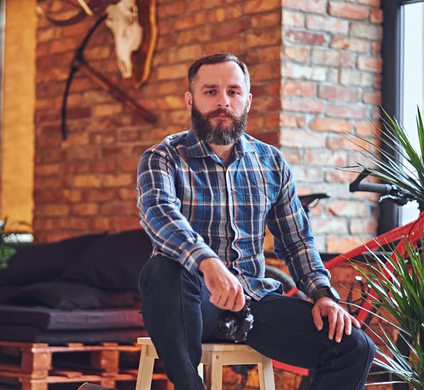 A bearded hipster male on a wooden chair