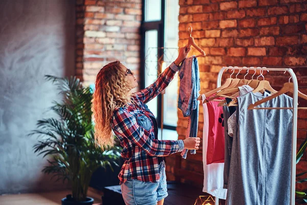 Vrouwtje kiest kleding op de kapstok — Stockfoto