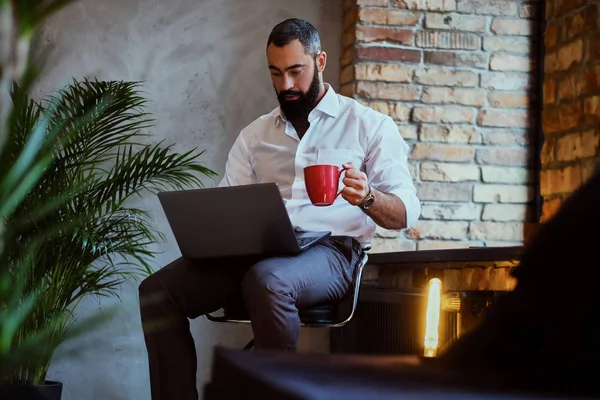 El hombre bebe café y usa una computadora portátil — Foto de Stock