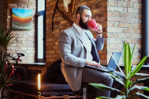 Чоловік п'є каву і використовує ноутбук — стокове фото