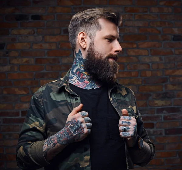 Татуированный бородатый мужчина в военной куртке . — стоковое фото