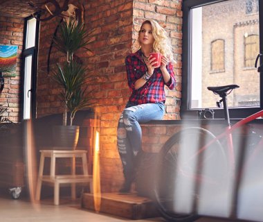 Sarışın kadın pencerenin sıcak kahve içer.