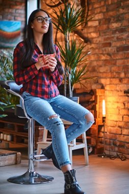 Bir kadın çatı iç ile bir odada kahve içer.