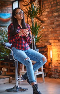 Bir kadın çatı iç ile bir odada kahve içer.