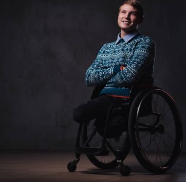 Gri arka plan üzerinde tekerlekli sandalyede bir adam.