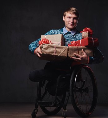 Noel hediyeleri ile tekerlekli sandalyede bir adam.