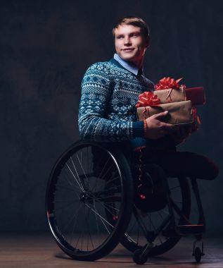Noel hediyeleri ile tekerlekli sandalyede bir adam.