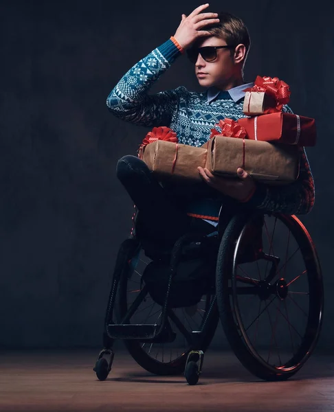 Un homme en fauteuil roulant avec des cadeaux de Noël . — Photo