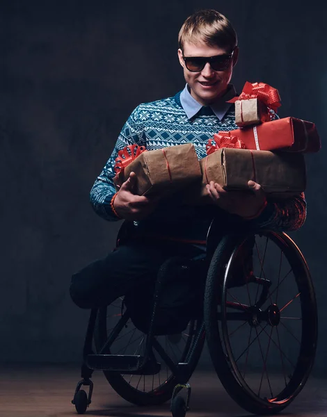 A man in wheelchair with Christmas gifts.