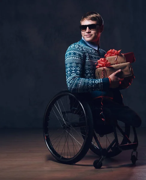 A man in wheelchair with Christmas gifts.