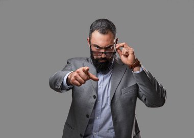 Ciddi, sakallı bir erkek bir gri takım elbise giymiş.