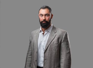 Ciddi, sakallı bir erkek bir takım elbise giymiş.