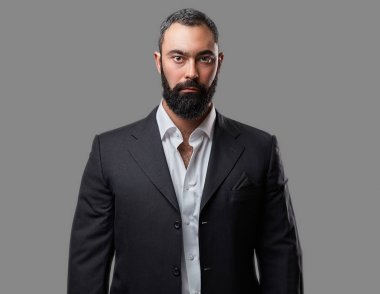 Ciddi, sakallı bir erkek bir takım elbise giymiş.