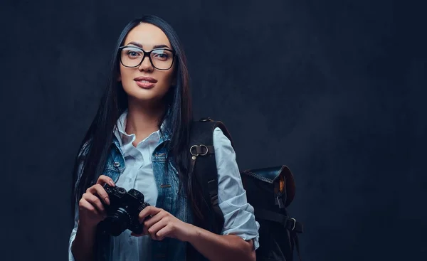 Een vrouw met rugzak houdt compacte fotocamera. — Stockfoto