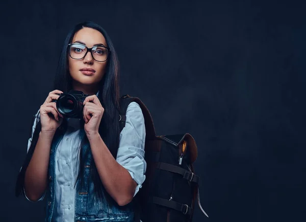 Uma mulher com mochila possui câmera fotográfica compacta . — Fotografia de Stock