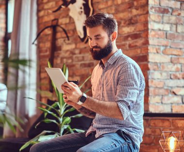 Çatı katı iç ile bir odada Tablet Pc kullanan adam.