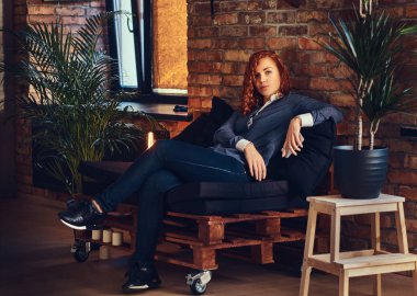 Kızıl saçlı kadın kanepede rahatlatıcı.