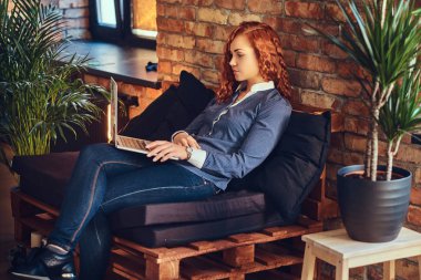 Kızıl saçlı bir dizüstü kullanan kadın.