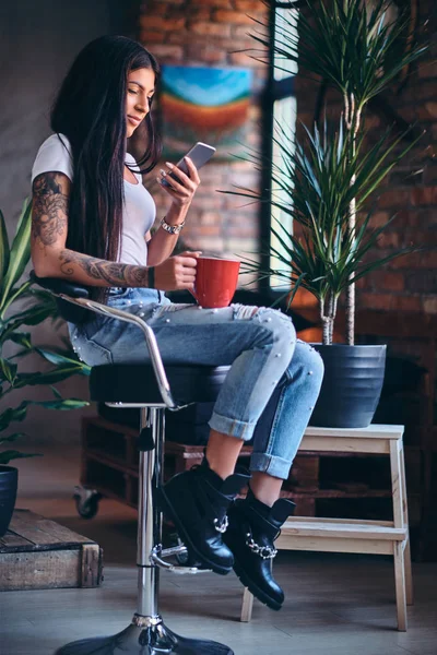 Tattooed brunette female drinks coffee