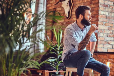 Çatı katı iç ile bir odada Smartphone kullanarak çekici sakallı casual erkek.