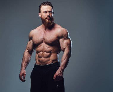 Sakallı gömleksiz vücut geliştirmeci gri arka plan üzerinde portresi.