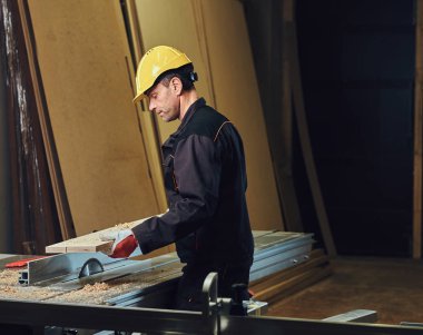 Sarı kap testere bir garajda çalışır bir emanet marangoz erkek giymiş.