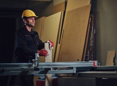 Sarı kap testere bir garajda çalışır bir emanet marangoz erkek giymiş.