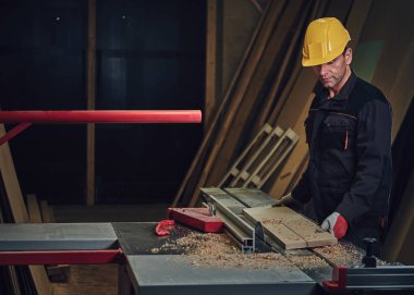 Sarı kap testere bir garajda çalışır bir emanet marangoz erkek giymiş.