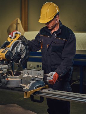 Sarı kap testere bir garajda çalışır bir emanet marangoz erkek giymiş.